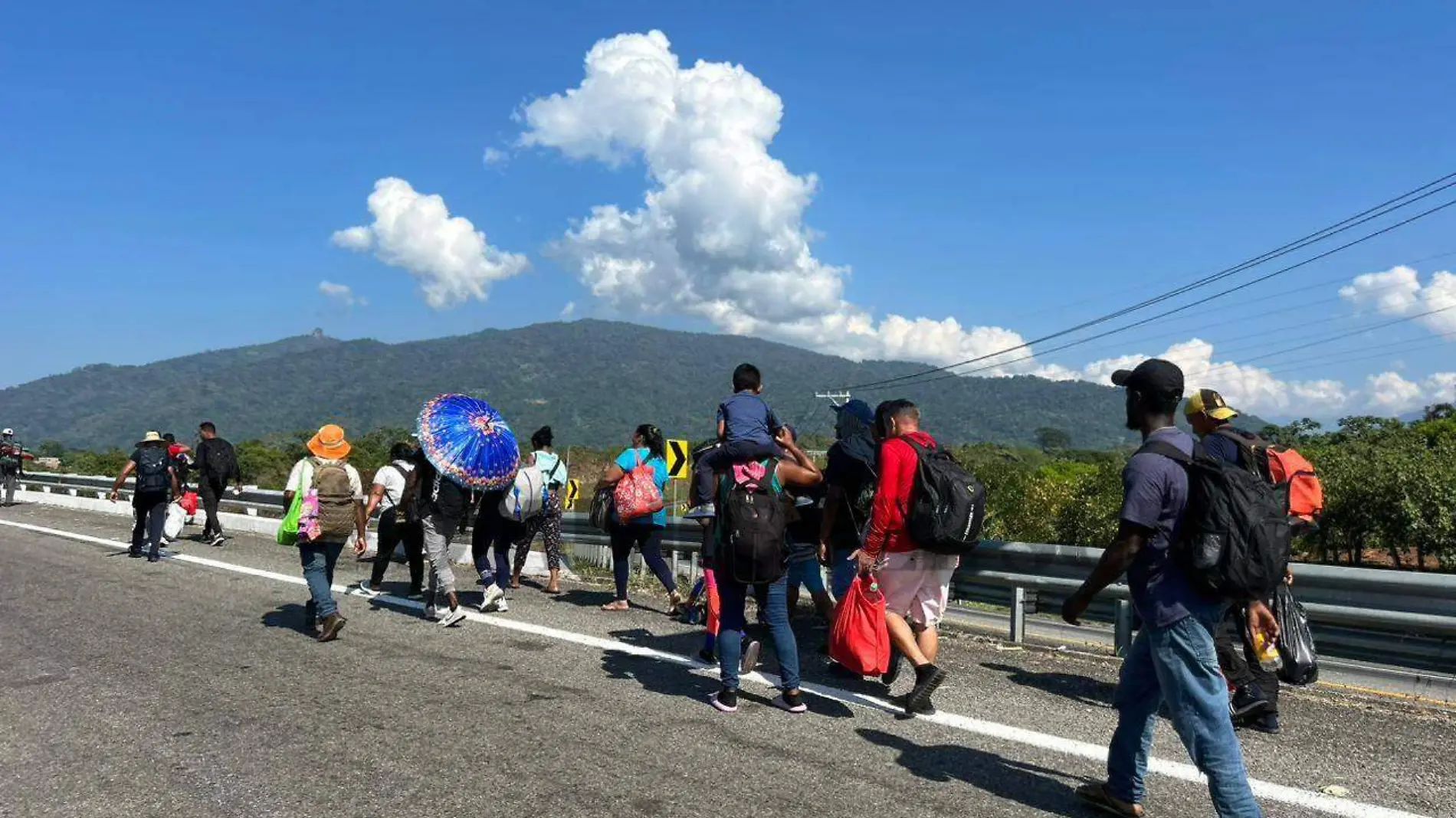 Migrantes caminando en la carretera costera